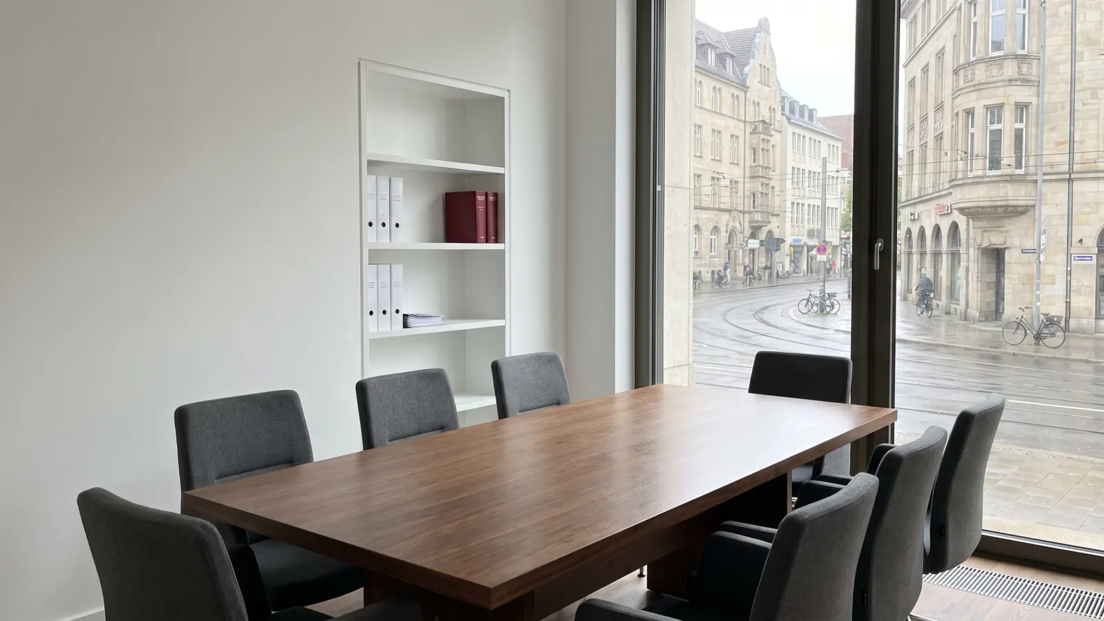 Besprechungsraum der Kanzlei mit langem Holztisch und Blick auf die Straße