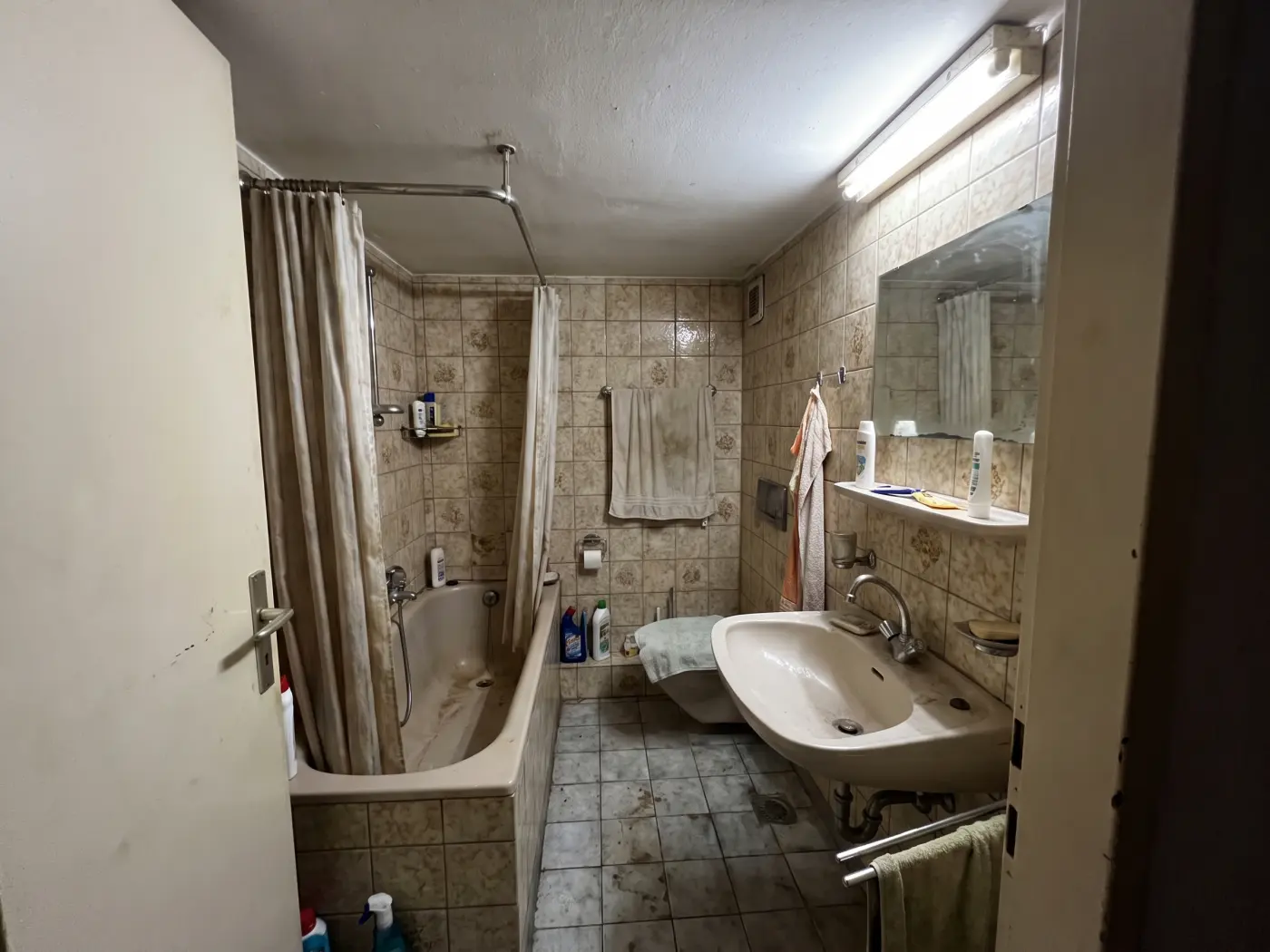 Bad vor der Sanierung mit gemusterten Fliesen aus den Achtzigern und Badewanne