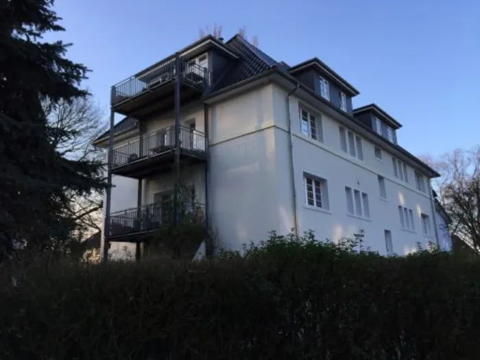 Weißes Mehrfamilienhaus mit Balkonen nach der Sanierung