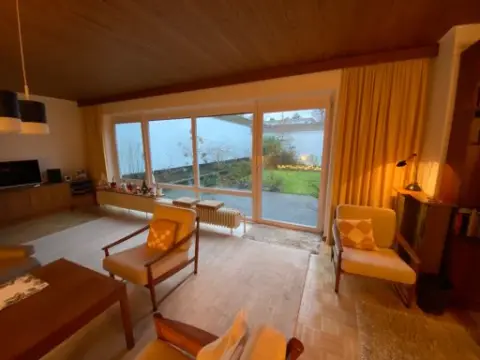 Wohnbereich des Bungalows vor der Sanierung, dunkle Holzverkleidung